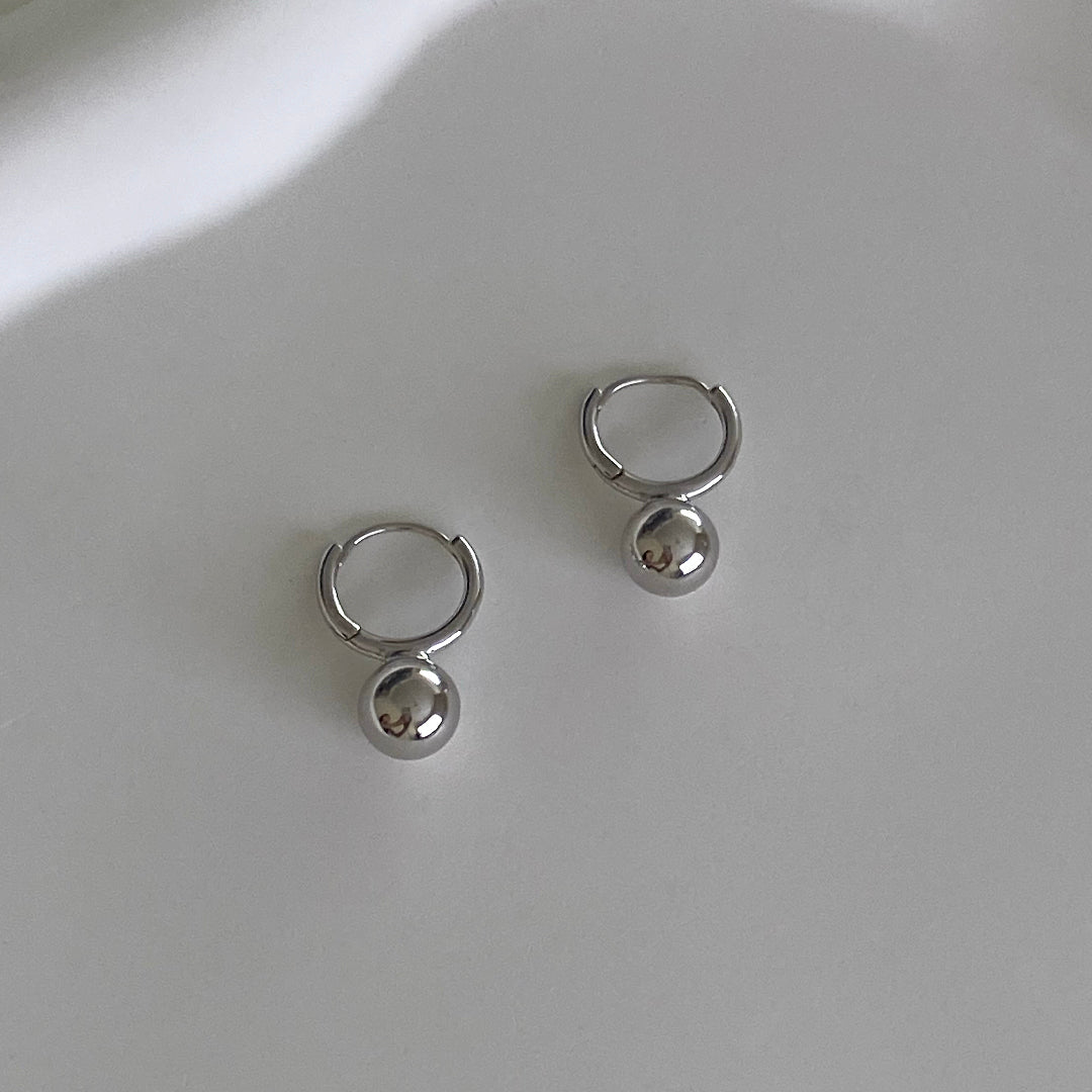 Front View of Mini Ball Huggies featuring small hoop earrings with a ball detail.