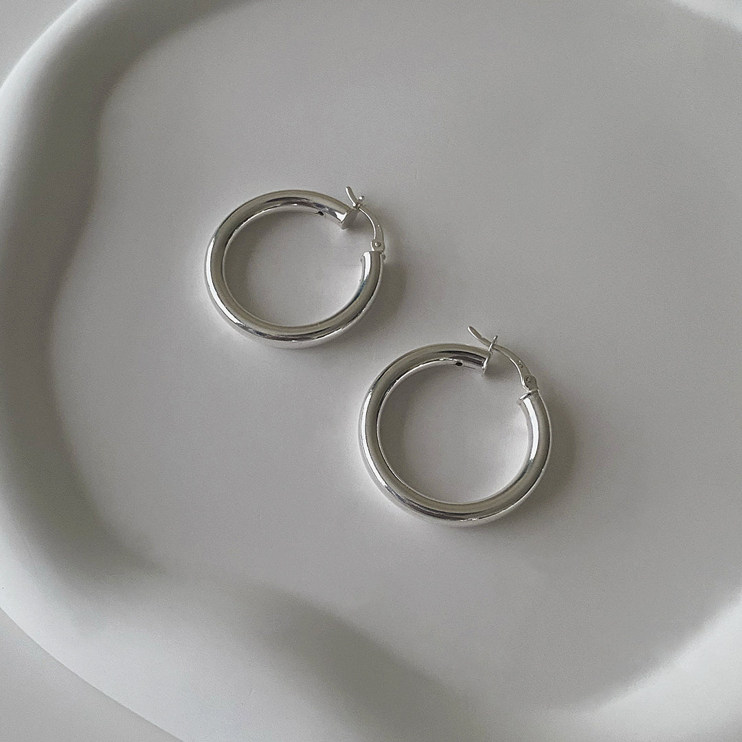 Angle view of CHESI 925 sterling silver Classic Tube Hoops in 30mm on a tray.