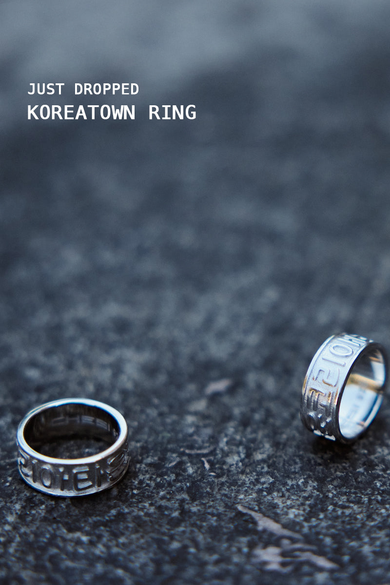 Two CHESI 925 sterling silver Koreatown rings on a concrete surface