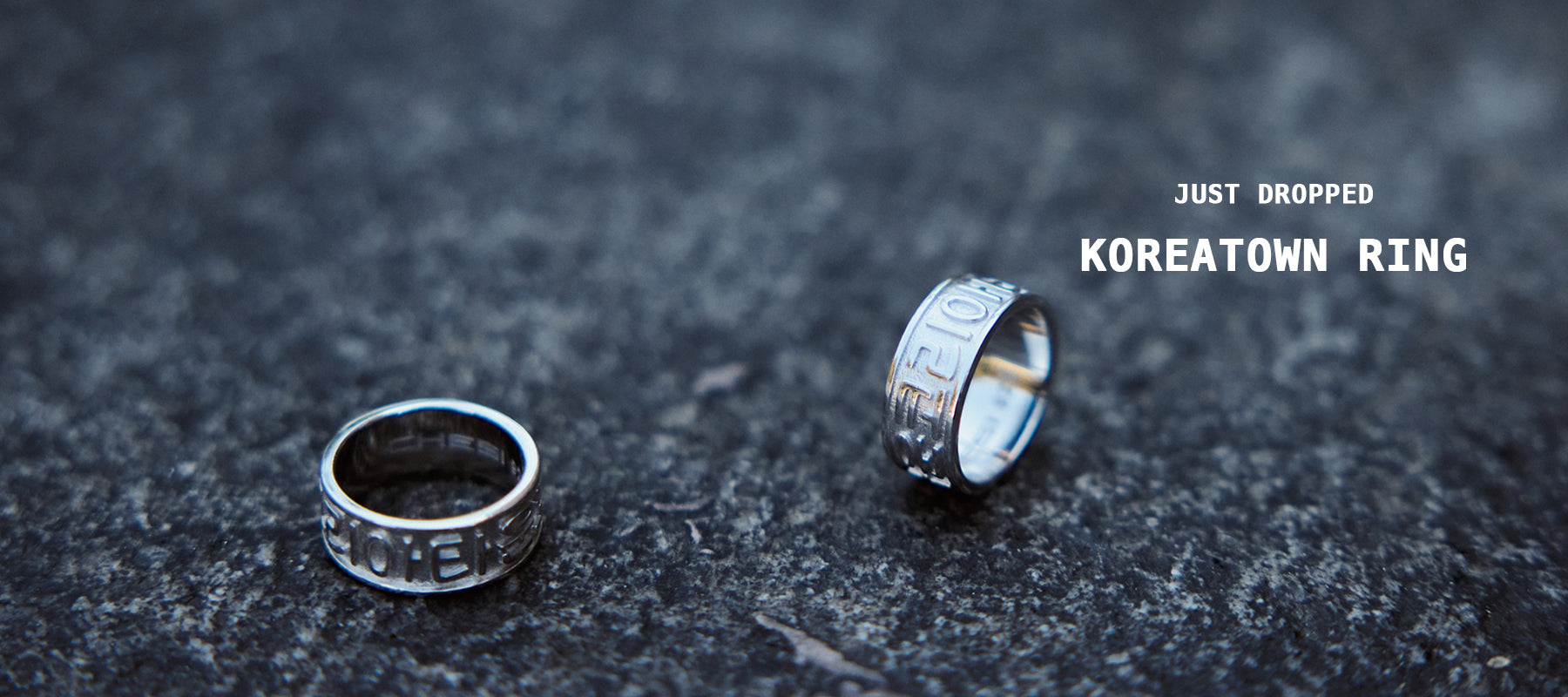 Two CHESI 925 sterling silver Koreatown rings on a concrete surface