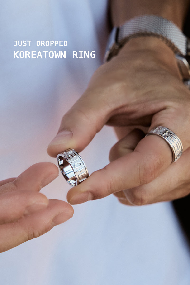 Close-up of male model in white t-shirt wearing CHESI 925 sterling silver Koreatown ring while adding another ring.
