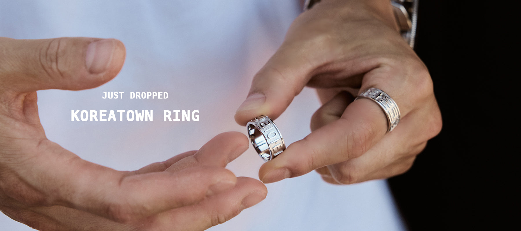 Close-up of male model in white t-shirt wearing CHESI 925 sterling silver Koreatown ring while adding another ring.