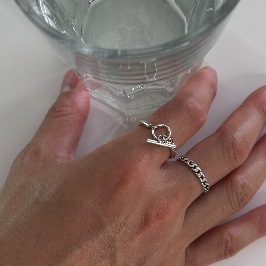 CHESI 925 sterling silver Toggle Ring and Thin Cuban Ring worn on male model’s hand next to a cup of water.