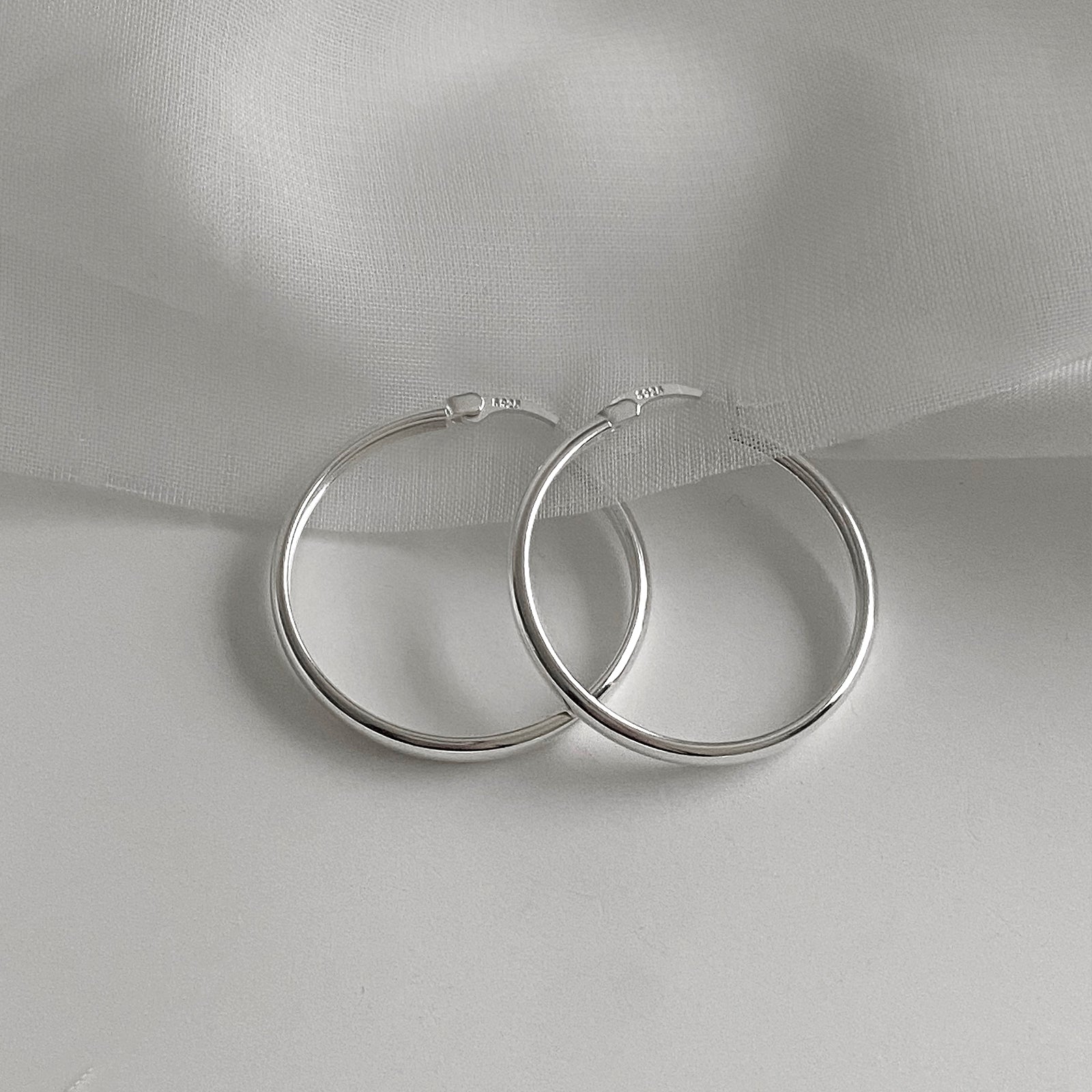 Top View of Jane Hoops size 30mm. These are classic hoop earrings with a latch back for closure. Has a S925 stamp on the latch. These hoop earrings are made of 925 Sterling Silver and has a smooth and shiny finish.